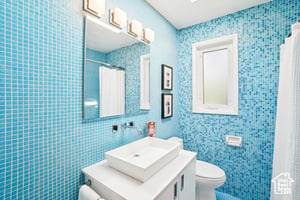 Full bathroom with toilet, vanity, a shower with curtain, and tile walls