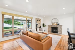 Living room featuring wood finished floors, a fireplace with raised hearth, and recessed lighting