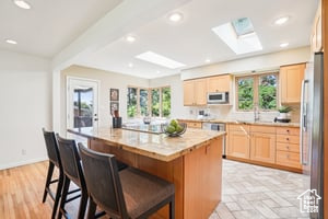 Kitchen with a skylight, plenty of natural light, stainless steel appliances, light countertops, and recessed lighting