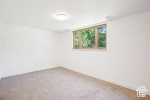 Carpeted spare room featuring baseboards