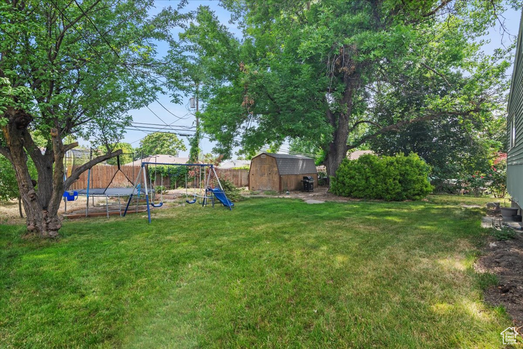 View of yard featuring a trampoline and a playground