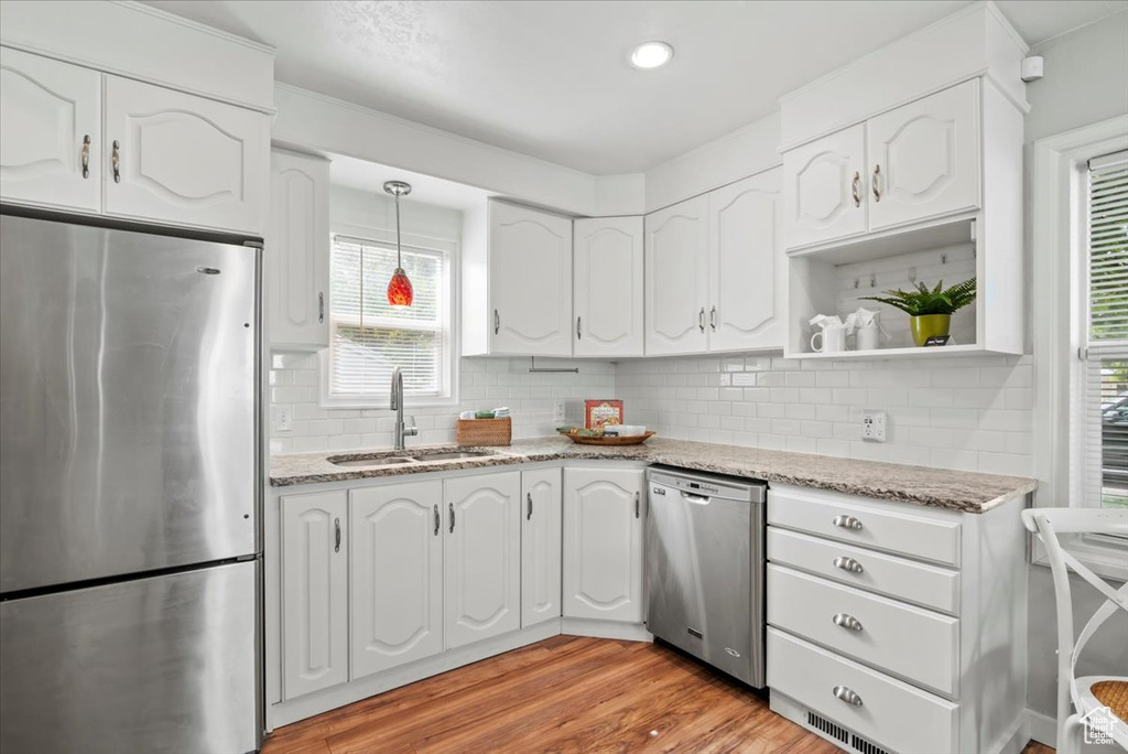 Kitchen with stainless steel appliances, a sink, white cabinets, and recessed lighting