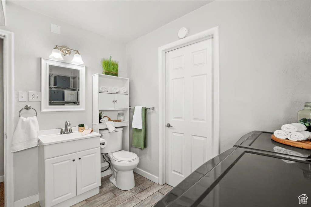 Bathroom with vanity, baseboards, wood finished floors, and toilet