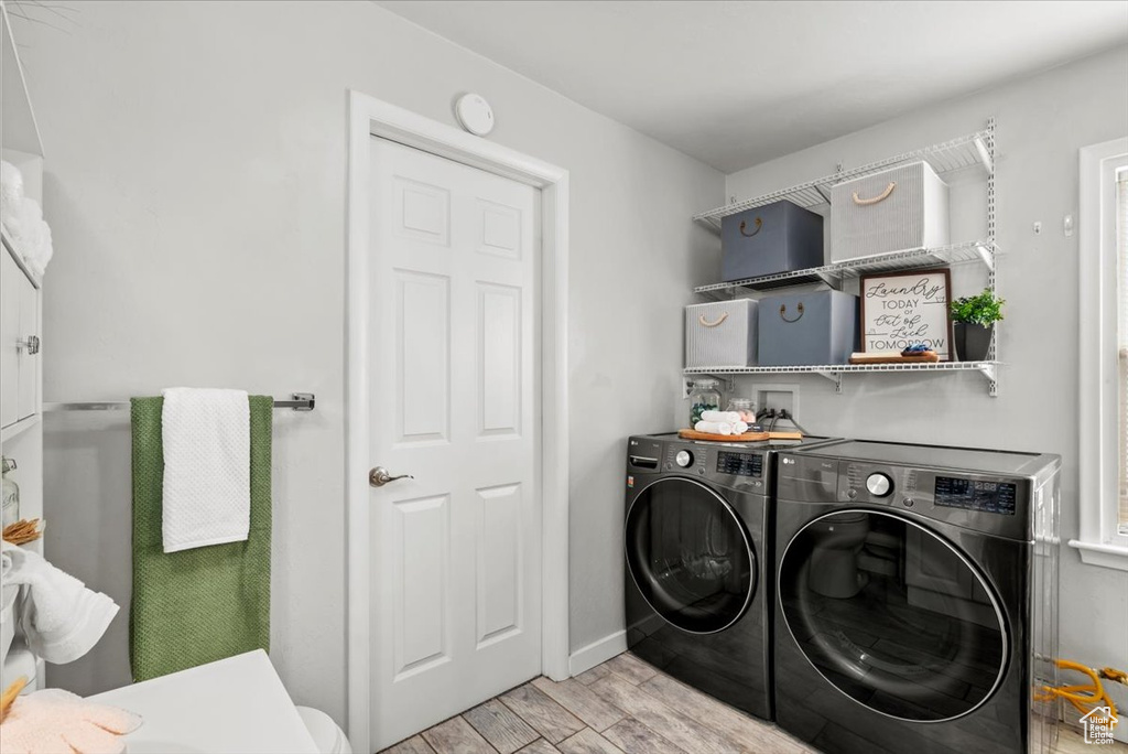 Laundry area with washing machine and dryer, light wood-style flooring, and baseboards