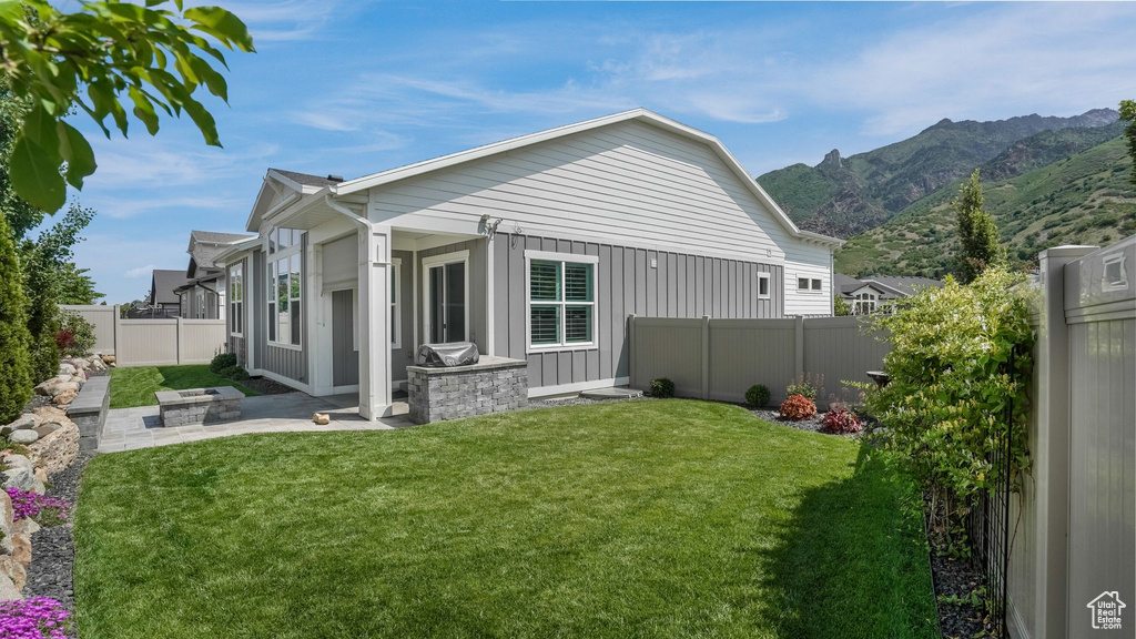 Back of property with a mountain view, board and batten siding, and a patio