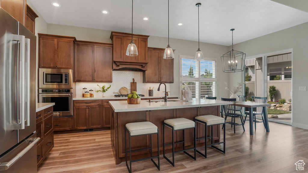 Kitchen featuring stainless steel appliances, light wood-style floors, a kitchen bar, light countertops, and recessed lighting