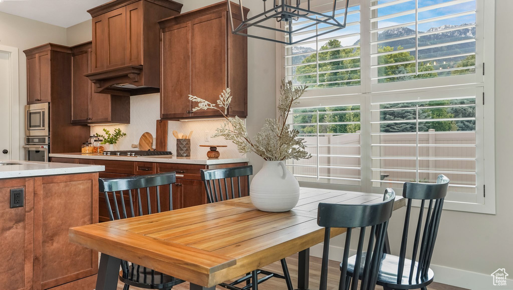 Kitchen with appliances with stainless steel finishes, light countertops, brown cabinets, a chandelier, and tasteful backsplash