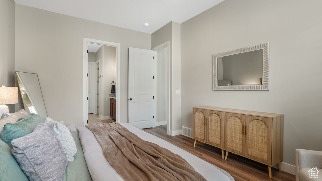 Bedroom with wood finished floors, baseboards, and ensuite bathroom