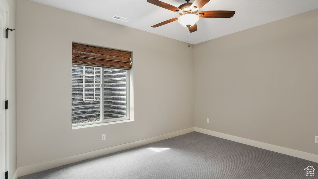 Carpeted empty room with a ceiling fan and baseboards