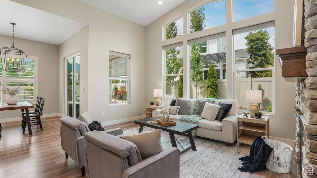 Living area with a chandelier, light wood-style flooring, baseboards, and vaulted ceiling