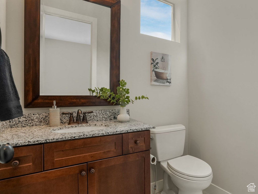 Half bathroom featuring toilet, vanity, and baseboards