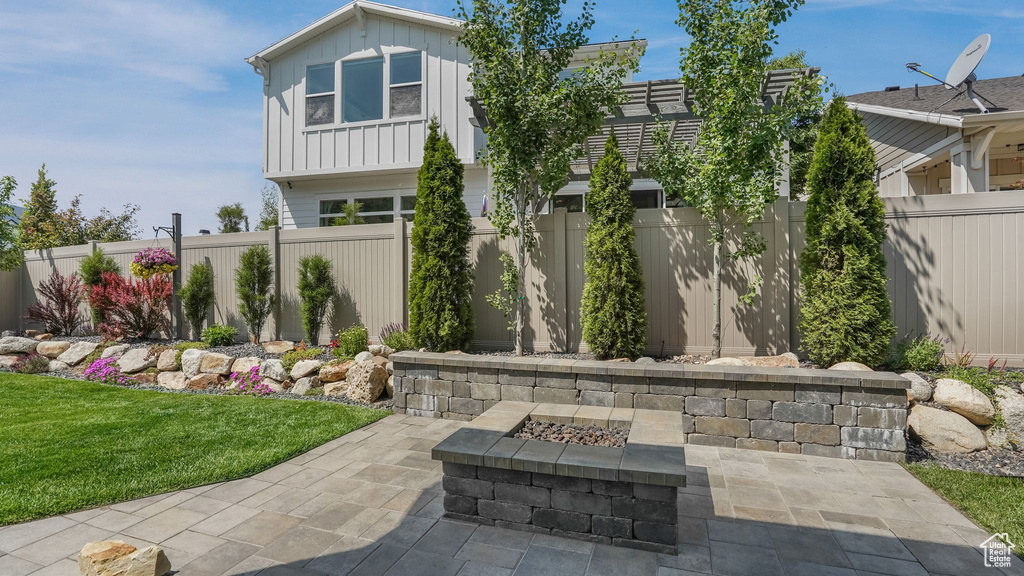 Fenced backyard featuring an outdoor fire pit and a patio