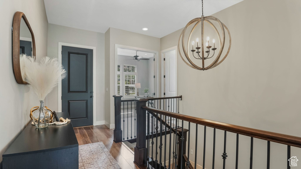 Hall featuring an upstairs landing, a chandelier, dark wood-style flooring, and baseboards
