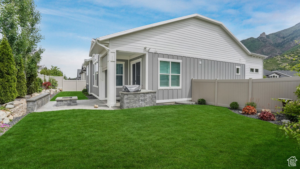 Back of property with a patio, an outdoor fire pit, a mountain view, and board and batten siding