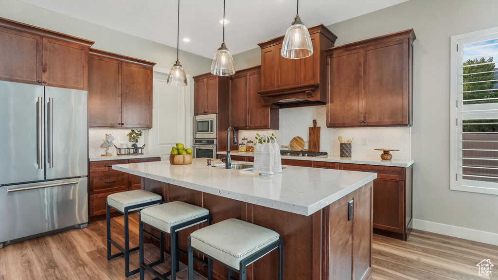 Kitchen featuring appliances with stainless steel finishes, light wood-style flooring, decorative backsplash, a kitchen breakfast bar, and recessed lighting