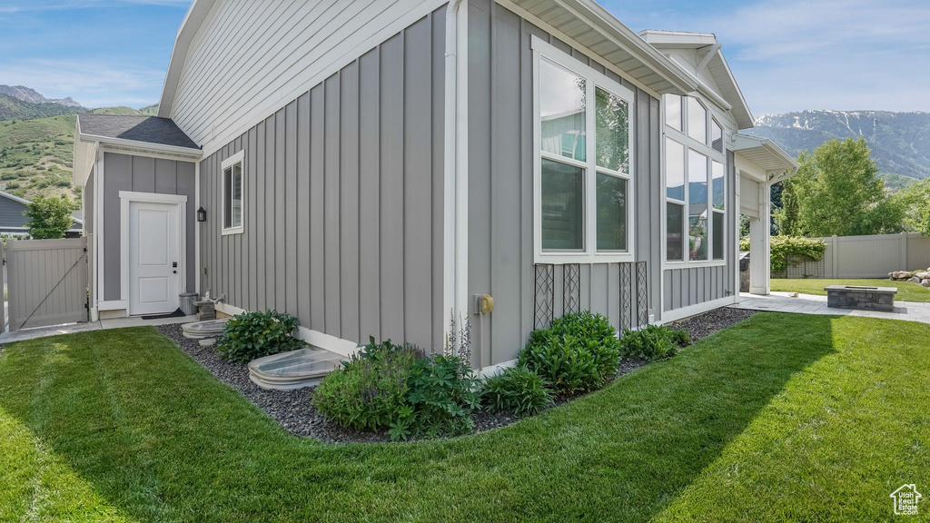 View of property exterior featuring board and batten siding, an outdoor fire pit, a mountain view, and a gate