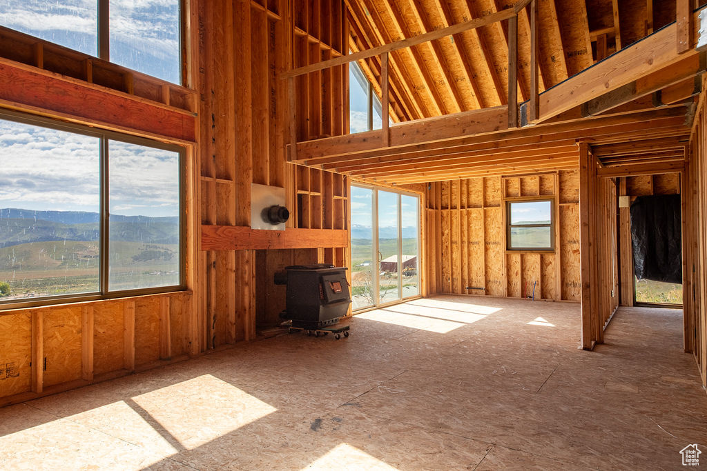 Unfurnished living room featuring a wood stove, plenty of natural light, a high ceiling, and a mountain view