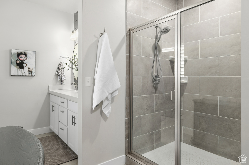 Bathroom featuring vanity, a shower stall, and baseboards