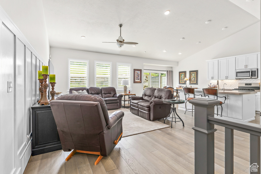 Living room featuring ceiling fan, recessed lighting, light wood-type flooring, and vaulted ceiling
