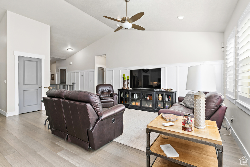 Living room with a ceiling fan, light wood-type flooring, and vaulted ceiling