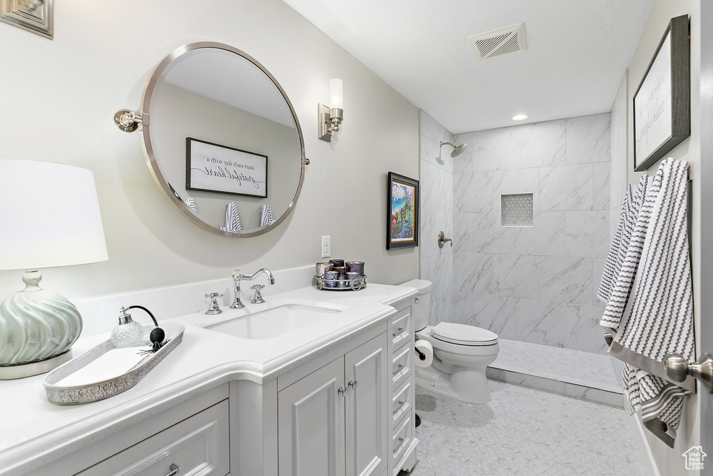 Full bath featuring toilet, vanity, a tile shower, and recessed lighting