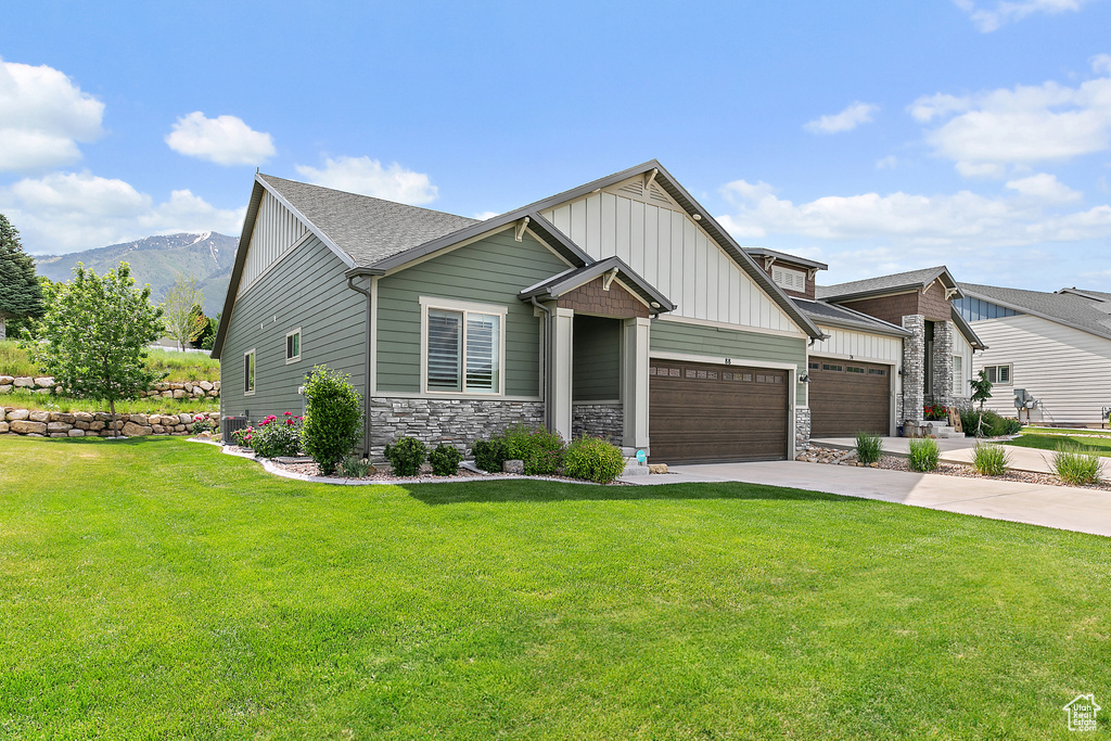 Craftsman house with board and batten siding, a garage, a front yard, and driveway