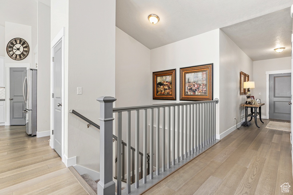 Hall featuring an upstairs landing, wood finished floors, and baseboards