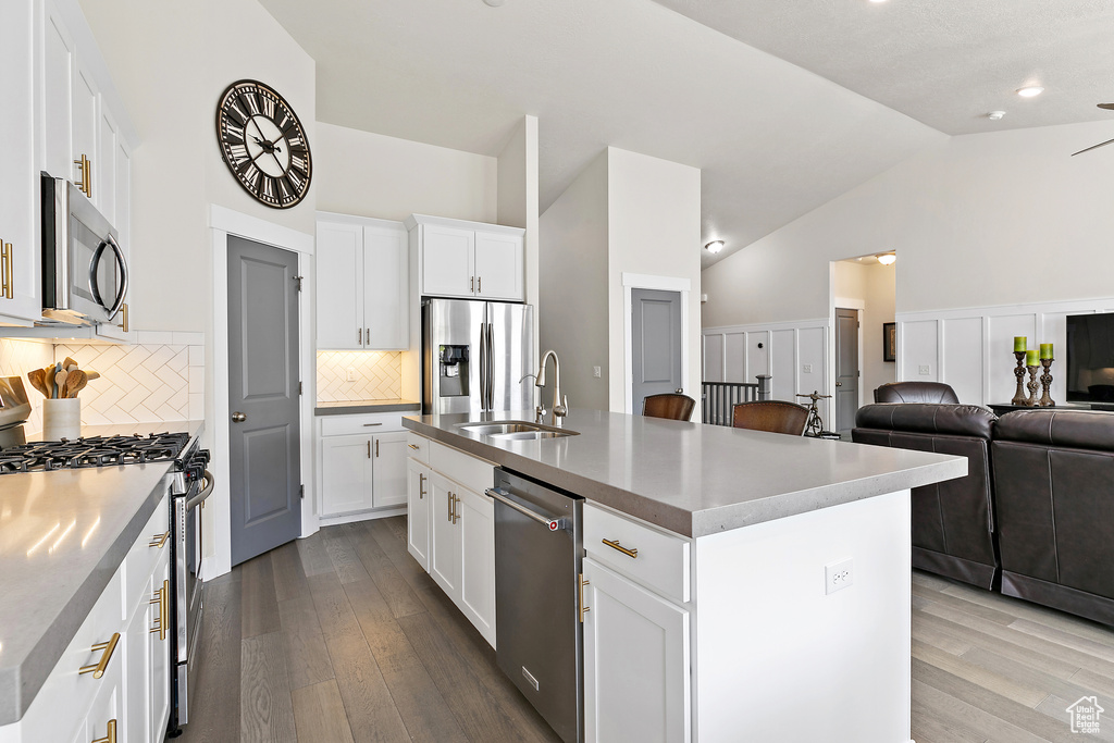 Kitchen featuring appliances with stainless steel finishes, a sink, dark wood-style flooring, tasteful backsplash, and white cabinetry