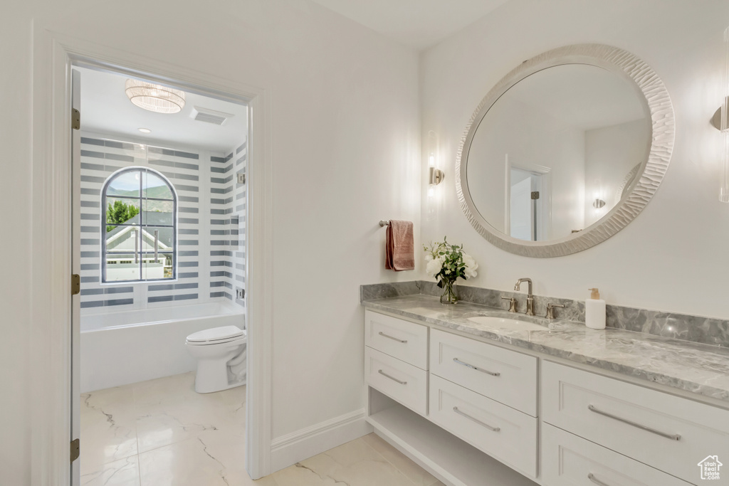 Bathroom featuring vanity, marble finish floors, and a bathtub