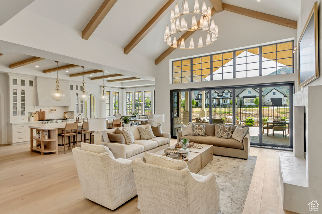 Living area featuring beam ceiling, a chandelier, light wood finished floors, a towering ceiling, and recessed lighting
