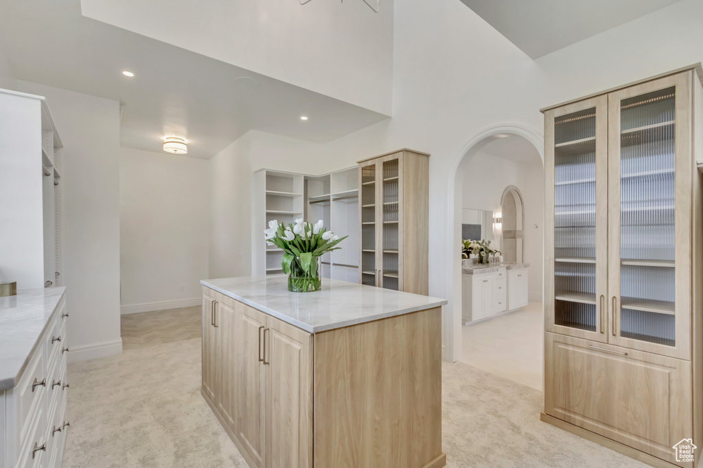 Kitchen with light colored carpet, light brown cabinets, arched walkways, a kitchen island, and recessed lighting