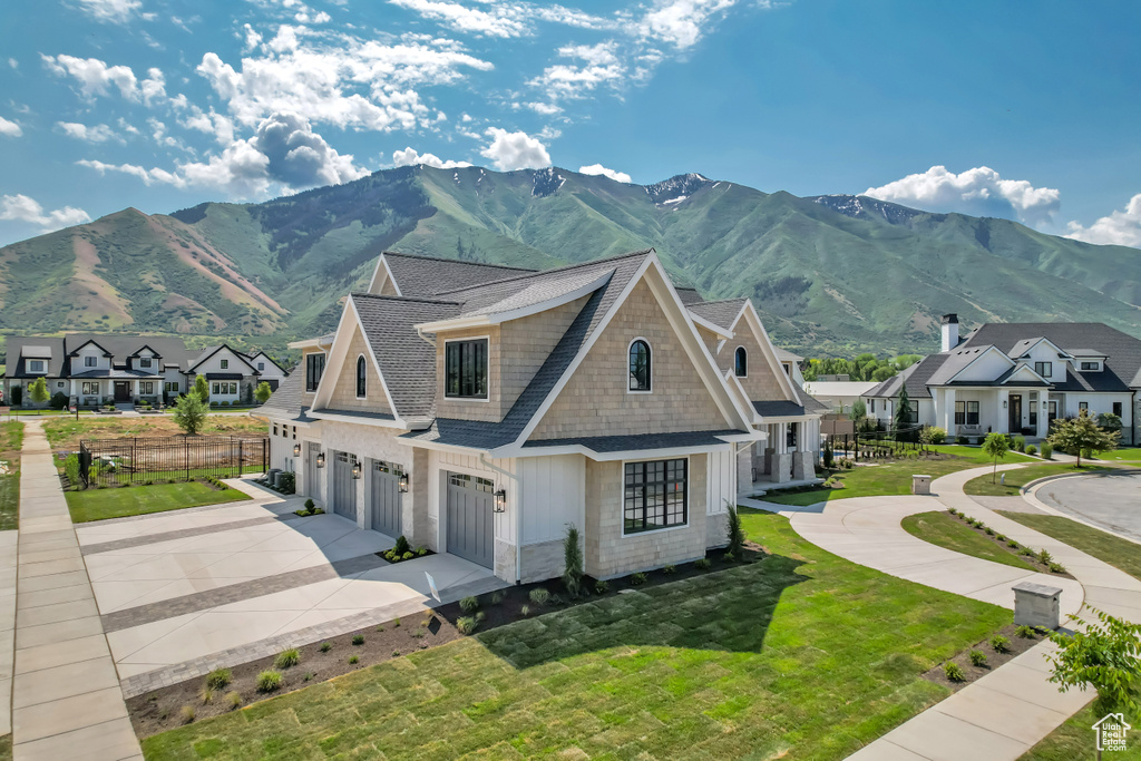 View of front of house featuring an attached garage, concrete driveway, a mountain view, and a residential view