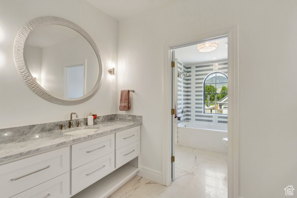 Full bathroom featuring marble look tiles, vanity, and a bath