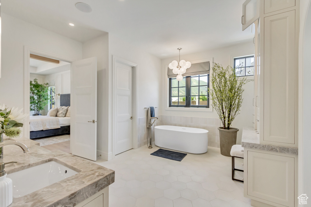 Ensuite bathroom with double vanity, a freestanding tub, a chandelier, tile patterned flooring, and recessed lighting