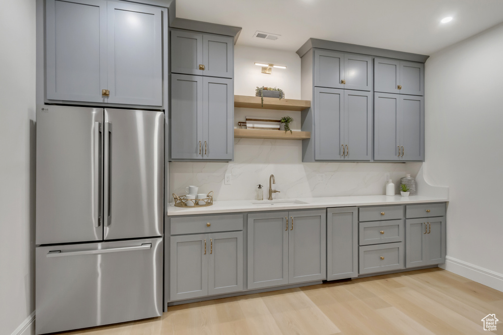 Kitchen with freestanding refrigerator, gray cabinetry, light countertops, decorative backsplash, and recessed lighting