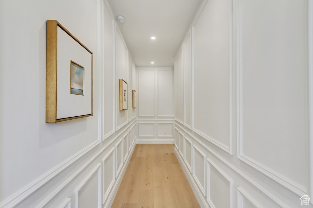 Corridor featuring a decorative wall, light wood-style floors, and recessed lighting