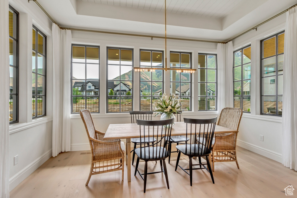 Sunroom with a tray ceiling, wood finished floors, and baseboards