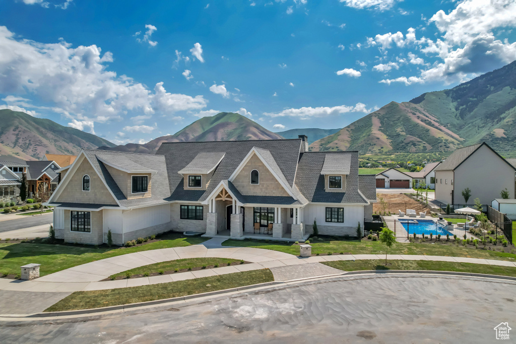 Shingle-style home featuring a mountain view, a front yard, and roof with shingles