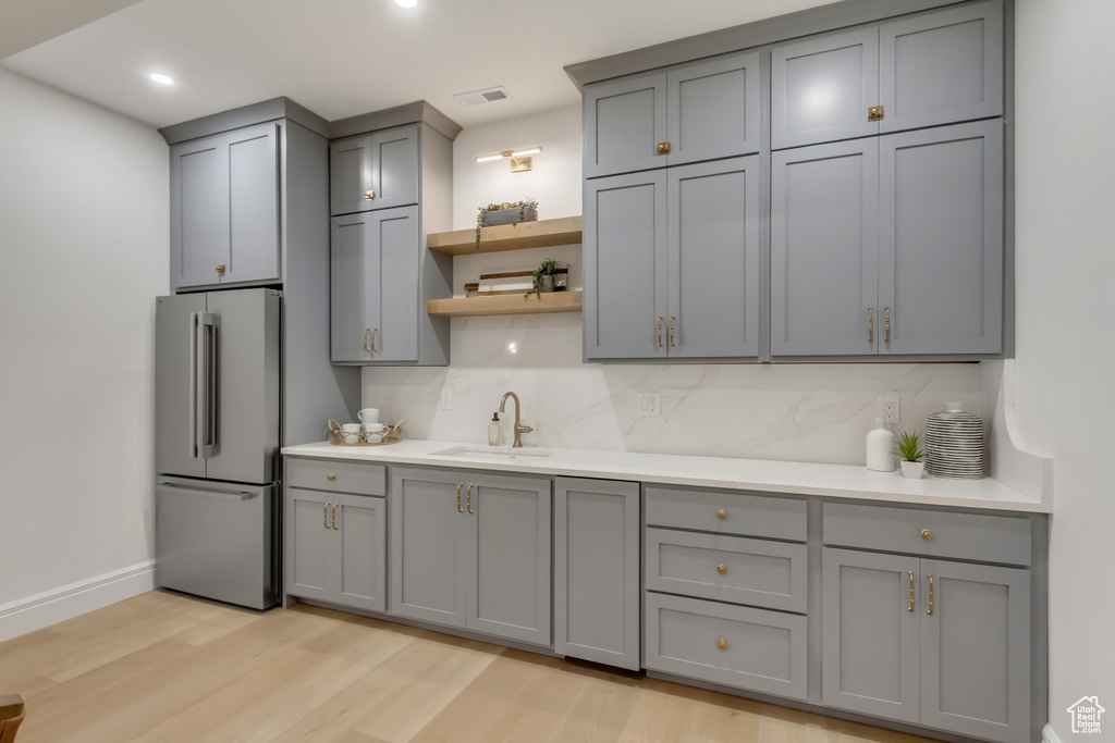 Kitchen featuring freestanding refrigerator, gray cabinetry, decorative backsplash, light wood-style floors, and recessed lighting