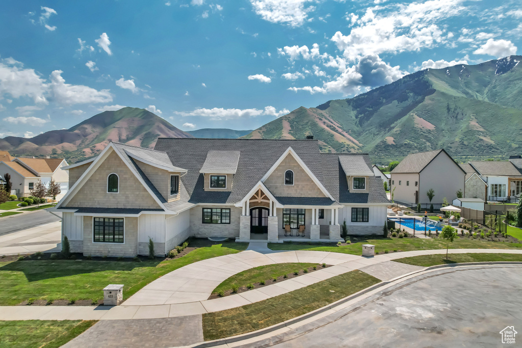 Shingle-style home featuring a mountain view, a front lawn, an outdoor pool, roof with shingles, and board and batten siding