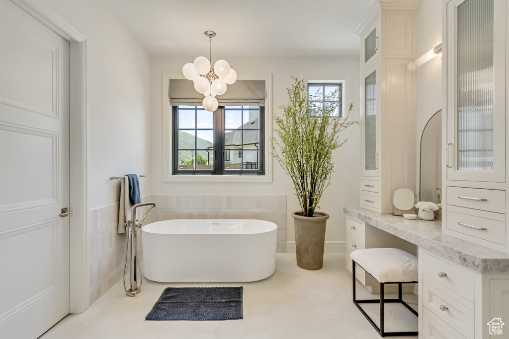 Bathroom with plenty of natural light, a freestanding bath, a chandelier, and vanity