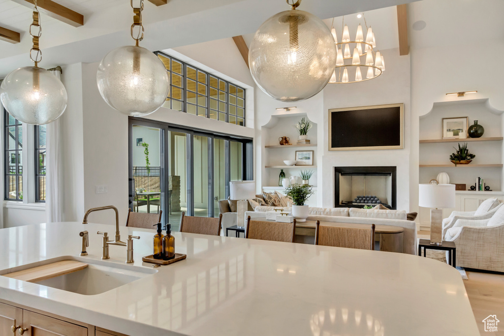 Kitchen with a sink, built in features, beamed ceiling, open floor plan, and light countertops