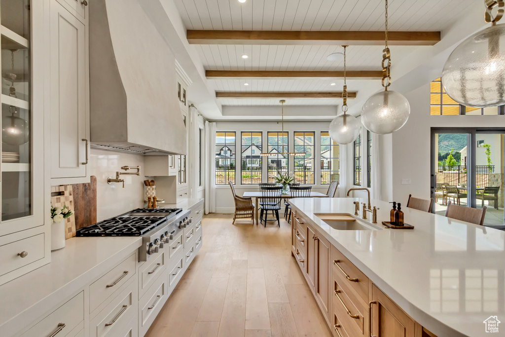Kitchen with a sink, wooden ceiling with exposed beams, plenty of natural light, light countertops, and light wood-style flooring
