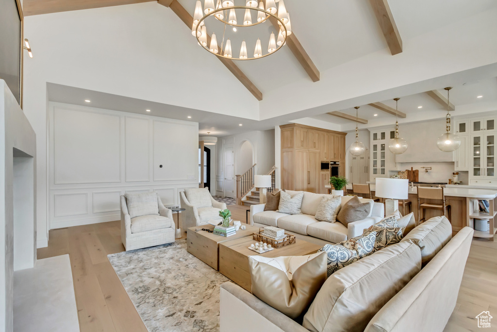 Living room with high vaulted ceiling, beam ceiling, a chandelier, light wood-style floors, and arched walkways