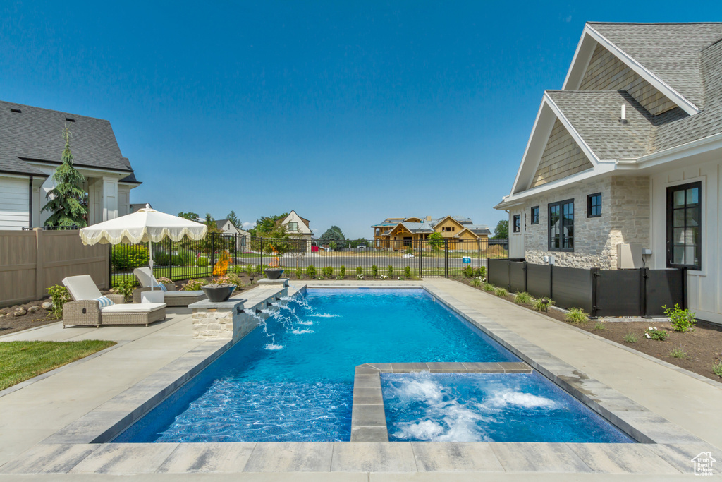 View of pool featuring a patio, a residential view, a fenced backyard, and a pool with connected hot tub
