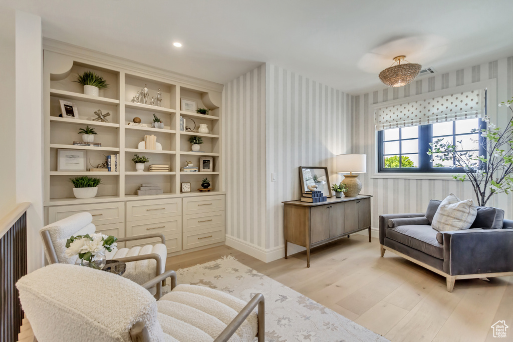 Living area with wallpapered walls and light wood-style flooring