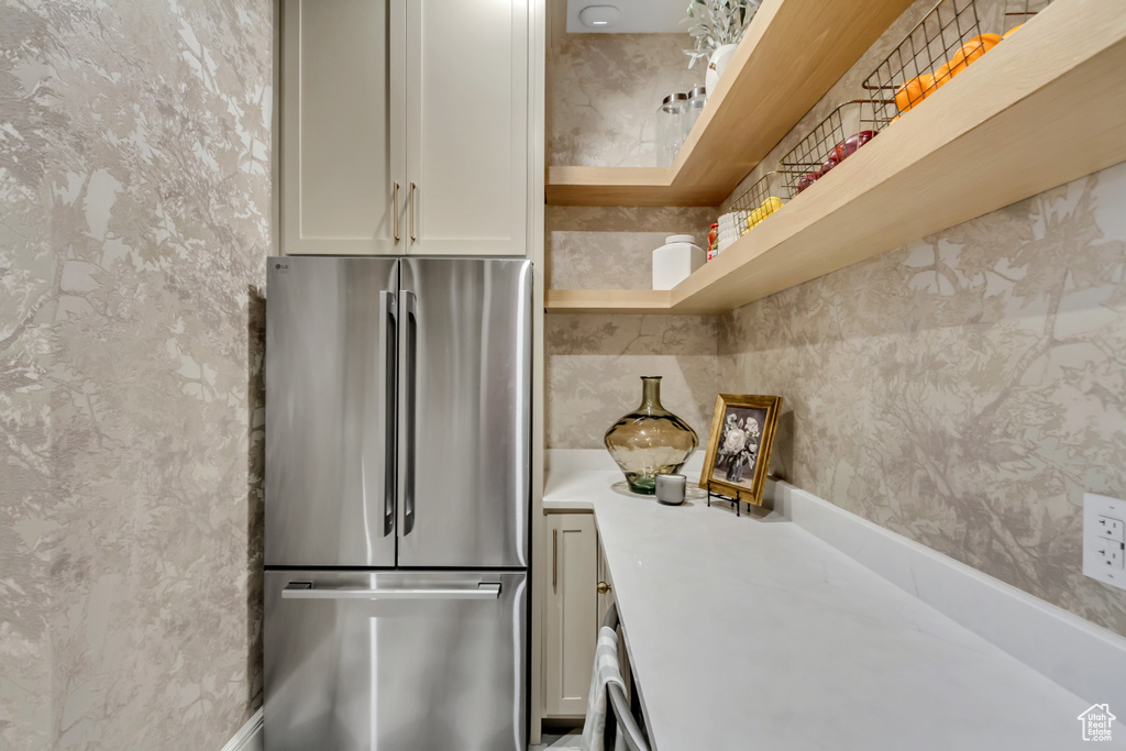 Kitchen with freestanding refrigerator, wallpapered walls, light countertops, and open shelves