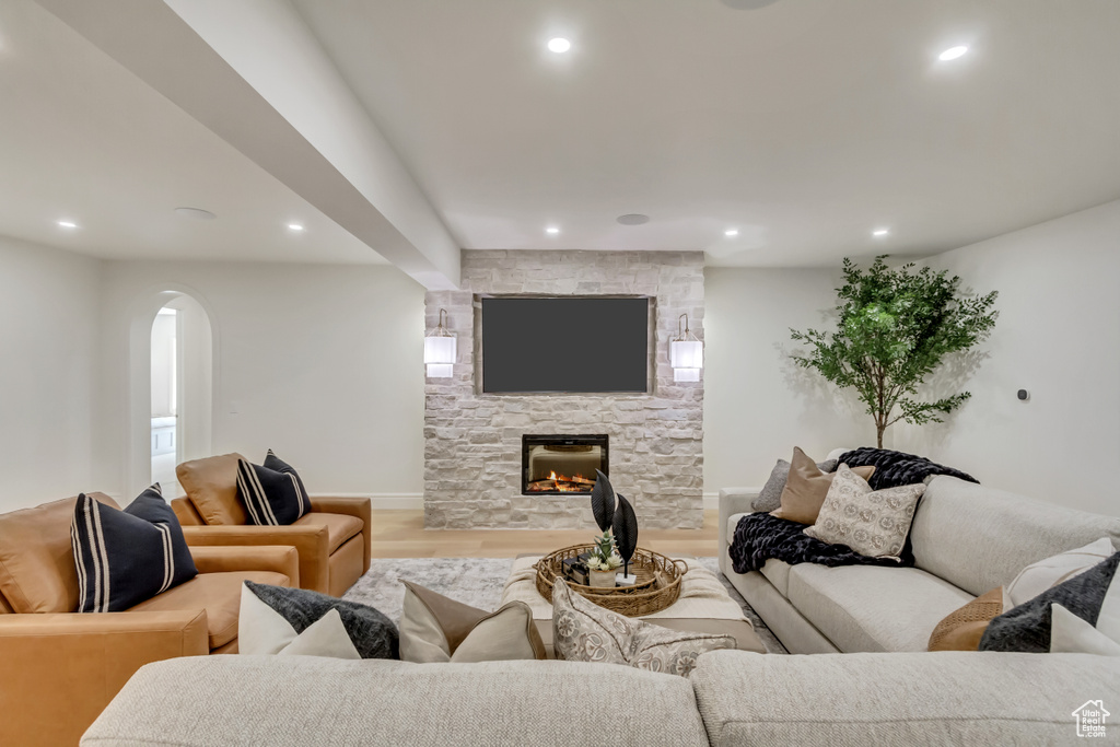 Living room with wood finished floors, arched walkways, recessed lighting, and a fireplace