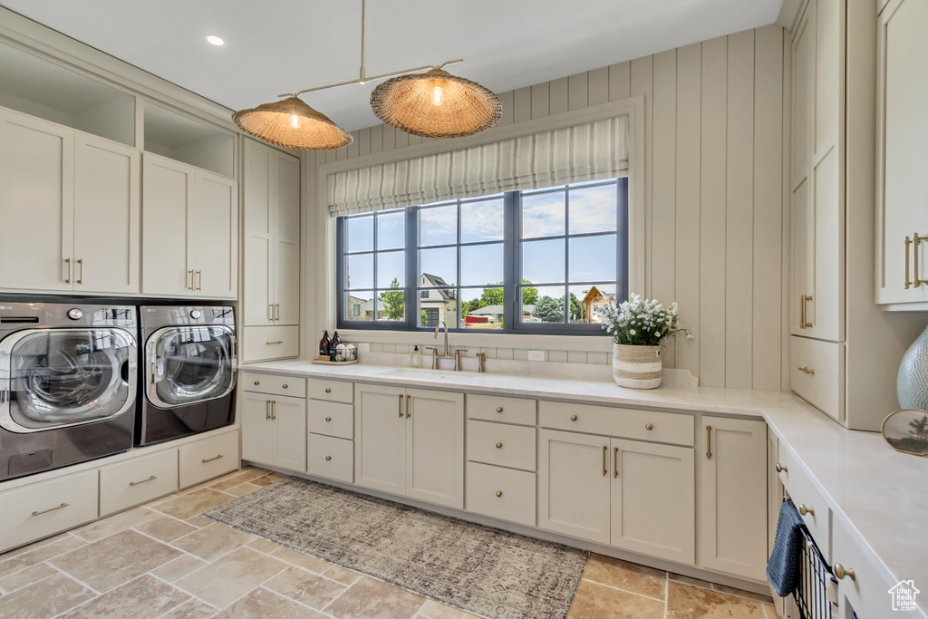 Laundry room with cabinet space, washer and clothes dryer, and stone tile floors