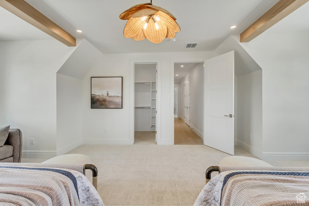 Bedroom featuring recessed lighting, light colored carpet, beamed ceiling, and a walk in closet